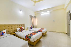 a hotel room with two beds and a couch at FabHotel RK Suites - Nr US Consulate, Financial District in Hyderabad