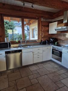 una cucina con mobili bianchi e una grande finestra di Rursee Eifel-Chalet mit Seeblick und Wellnessbereich a Simmerath
