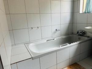 ein weiß gefliestes Badezimmer mit Badewanne und Waschbecken in der Unterkunft Terrys Cozy Homestay in Germiston + 23 Fotos