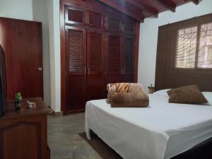 a bedroom with a bed with a chair and wooden cabinets at EpicBK Casa Campestre en San Pedro Antioquia in Zatra Tobón