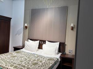 een hotelkamer met een bed met witte kussens bij Boulevard Palace Hotel in Samarkand