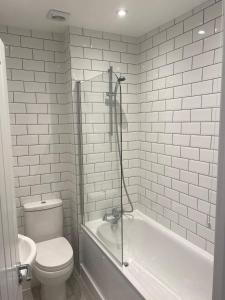 a white bathroom with a toilet and a bath tub at No 5 Accommodation in London