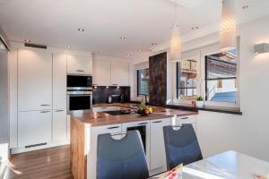 a kitchen with white cabinets and blue chairs at Ferienwohnung Oberladstätter in Wiesing