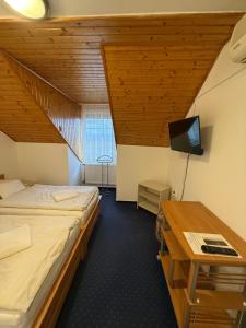 a room with a bed and a desk with a television at Panzió Pér in Pér