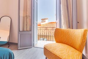 a yellow chair in a room with a balcony at Appartement moderne et élégant Michel Torrent 2 in Perpignan