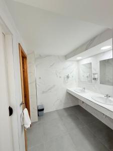 a white bathroom with two sinks and two mirrors at Hostal Quinta Santillan in San Fernando de Henares +88 photos