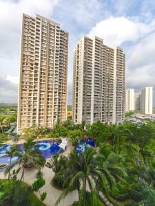 萨姆波罗Sky House BSD 3 Bedroom 70m2 View Pool Dan Garden的棕榈树环绕的城市中有两栋高楼