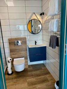 een badkamer met een wastafel, een toilet en een spiegel bij Apartamenty Czerwone Korale in Chłopy