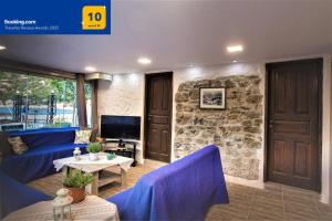 a living room with blue furniture and a stone wall at Private Beachfront House Irene Mare, Serene Views in Poros