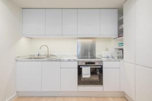a white kitchen with white cabinets and a sink at Stunning Central Apt With Parking in Cambridge