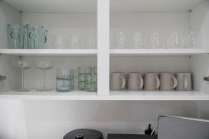 a shelf filled with glasses and wine glasses at Waterview apartments with ultra fast wifi close to Excel and O2, corporates and contractors welcome in London