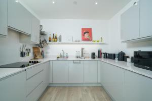 a white kitchen with white cabinets and appliances at Waterview apartments with ultra fast wifi close to Excel and O2, corporates and contractors welcome in London