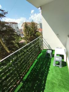 a balcony with green grass and a white chair at Bulevar Apartman BL in Banja Luka
