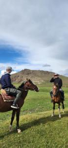 two people are riding horses in a field at Yurt camp KEREMET in Kyzart
