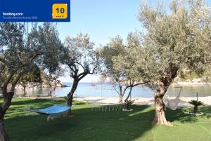 a hammock hanging between two trees near the water at Private Beachfront House Irene Mare, Serene Views in Poros