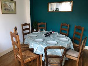 a dining room table with chairs and a blue wall at Chambre - Maison La Libéllule in Besançon