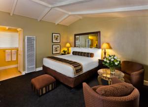 a hotel room with a large bed and chairs at Monterey Peninsula Inn in Pacific Grove
