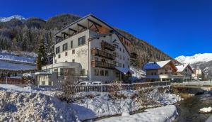 a large building in the snow next to a river at Hotel Edelweiss in Kaunertal