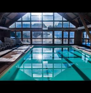 a large swimming pool with blue water in a building at Chalet Joue du loup 6-7 pers in Le Dévoluy +29 photos