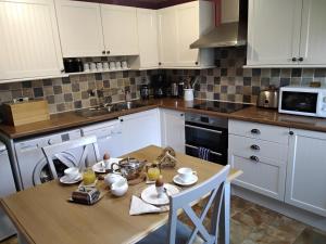 a kitchen with white cabinets and a wooden table at Top Floor at Cantref House in Brecon