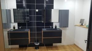 a bathroom with two sinks and a black tiled wall at Au refuge du Bonheur in Provenchères-sur-Fave +42 photos