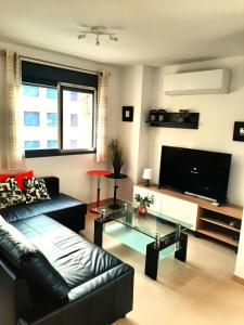 a living room with a black couch and a flat screen tv at Enjoy the beach in Bellreguart