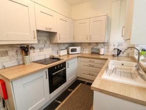 eine Küche mit weißen Schränken und einer Spüle in der Unterkunft Ednas Cottage in Ambleside