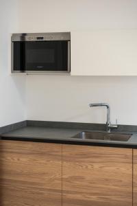 a kitchen with a sink and a microwave at Bilocale Gelsomino - Cascina Da Rosa in Capiago Intimiano