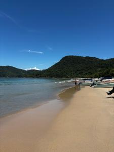 a beach with a group of people standing on the sand at Chalé Canoa in Paraty