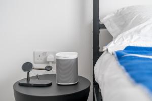 a bedroom with a bed and a table with a speaker on it at Waterview apartments with ultra fast wifi close to Excel and O2, corporates and contractors welcome in London
