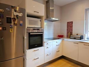 a kitchen with white cabinets and a stainless steel refrigerator at Modern duplex with garden in Brussels