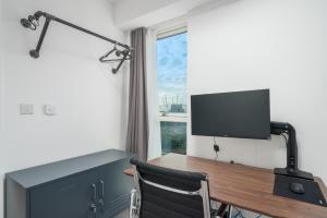 a room with a desk with a television and a chair at Waterview apartments with ultra fast wifi close to Excel and O2, corporates and contractors welcome in London