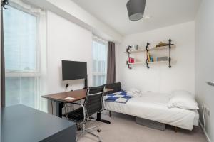 a bedroom with a bed and a desk and a computer at Waterview apartments with ultra fast wifi close to Excel and O2, corporates and contractors welcome in London
