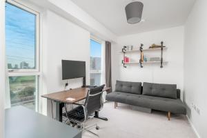 an office with a desk and a couch and a computer at Waterview apartments with ultra fast wifi close to Excel and O2, corporates and contractors welcome in London