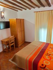 a bedroom with a bed and a table and a chair at Hotel Rural Real de Laroles Nevada bike and treeking in Laroles +26 photos