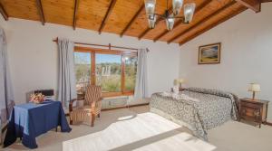 ein Schlafzimmer mit einem Bett und einem Tisch und einem Fenster in der Unterkunft Las Verbenas Hotel in La Cumbrecita