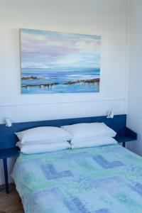 a bedroom with a blue bed with a painting on the wall at A Stone's Throw from the Ocean in Seafield