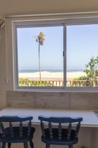two chairs in front of a window with a view of the beach at A Stone's Throw from the Ocean in Seafield