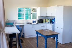 a kitchen with white cabinets and a wooden table at A Stone's Throw from the Ocean in Seafield