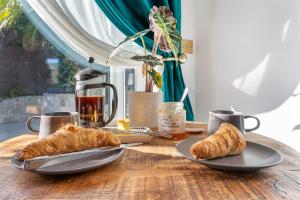 a table with two plates of croissants and coffee cups at 5 min walk to beach with parking and private sauna in Falmouth