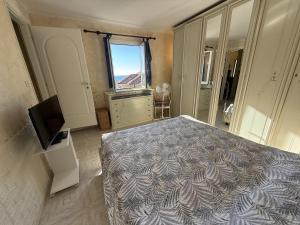 Un dormitorio con una cama y un televisor y una ventana. en The Piano Apartment - Beautiful View - by Host4U, en Imperia