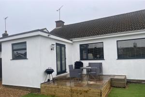 a white house with a table and chairs on a deck at Pet-Friendly - 2 Bedrooms Bungalow hot tub parking in Heacham