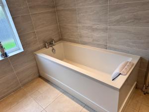 a white bath tub in a bathroom with a window at Pet-Friendly - 2 Bedrooms Bungalow hot tub parking in Heacham +39 photos