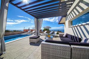 a patio with a couch and an umbrella and a pool at Villa Red with pool and sea view in Makarska