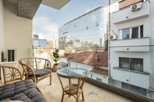 a balcony with a table and chairs and a large window at UpHome Suites in Bucharest