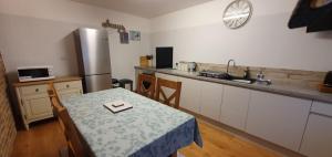 a kitchen with a table and a stainless steel refrigerator at Mulberry Cottage near Goodwood in Chichester