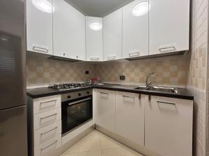 a kitchen with white cabinets and a sink at Casa Vacanze Asia Da Vinci's House in Fiumicino