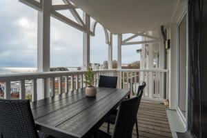 un portico con tavolo e sedie in legno sul balcone di Haus-Ostseeapartments-am-Fehmarnsund-Wohnung-24-SUeDSTRANDBLICK a Grossenbrode