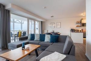 un soggiorno con un divano e un tavolo di Haus-Ostseeapartments-am-Fehmarnsund-Wohnung-24-SUeDSTRANDBLICK a Grossenbrode