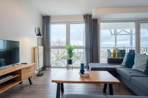 un soggiorno con un divano e una TV di Haus-Ostseeapartments-am-Fehmarnsund-Wohnung-24-SUeDSTRANDBLICK a Grossenbrode